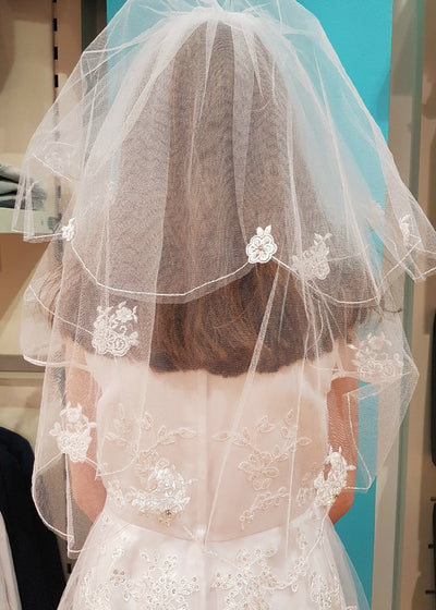 Truly stunning First Communion veil. A combination of woven flower motif and pearls embellish the tulle veil. Comb attached and ready to wear with or without a headpiece, and offers flexibility for different hair styles.